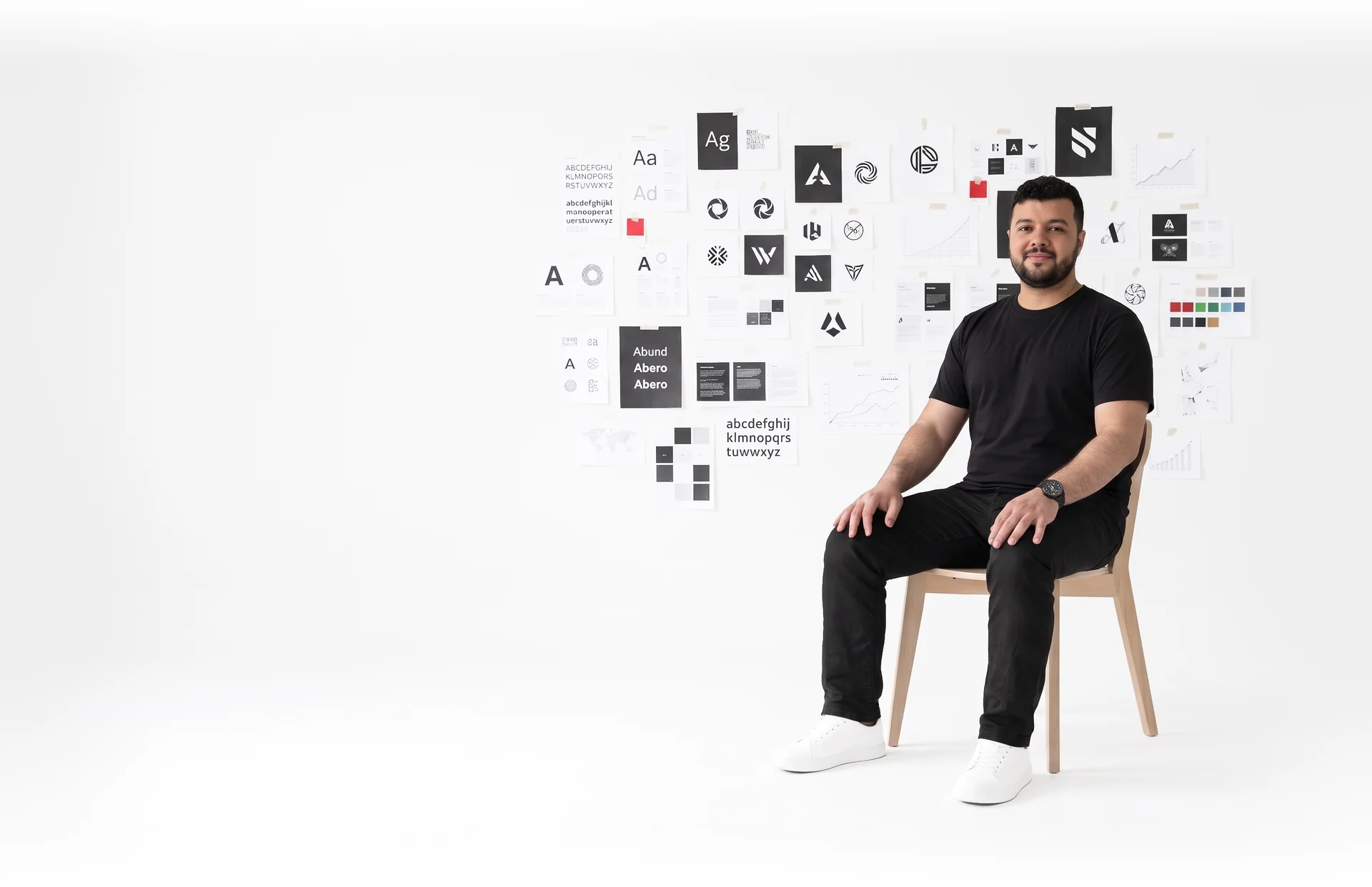 Basel Dalloul seated in front of a wall of brand identity work